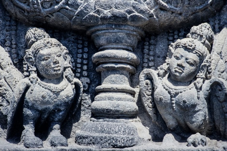 Close-up view of detailed stone carvings depicting two mythological figures in an Indonesian temple.