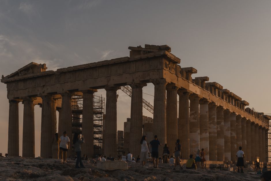 A captivating view of the Parthenon in Athens at sunset with visitors exploring the ancient site.