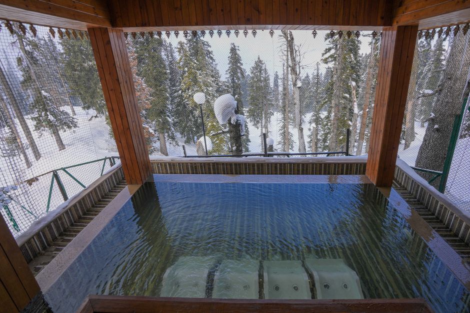 An inviting pool with a snowy forest backdrop, perfect for winter relaxation.